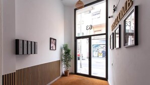 Un intérieur moderne avec un mur lambrissé en bois, une plante en pot et une grande porte vitrée portant l’inscription « BIENVENUE ».