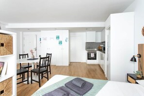 Un apartamento moderno con comedor, kitchenette y una cama con toallas.