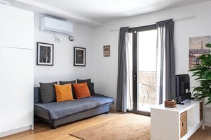 A modern living room with a sofa, a flat-screen TV, and a sliding glass door leading to a balcony. - StayCampNou Spacious 3BR Apt with Balcony · Camp Nou · Fira (L'Hospitalet de Llobregat)