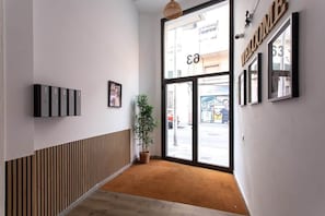 Ein modernes Interieur mit einer Wandpaneele aus Holz, einem Blumentopf und einer großen Glasdoor mit einem 'WELCOME'-Schild.