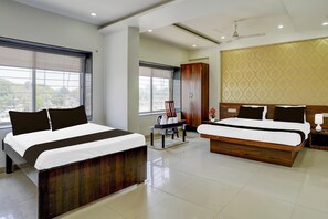 A hotel room with two beds, a wardrobe, a desk with a chair, and a large window. - Classic With Twin Bedhotel Shanti Datta inn (Nashik)