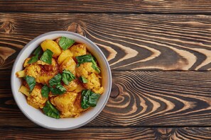 A bowl of food with potatoes and greens on a wooden table. - Classic With Balcony Mourigram Near Andul Road (Howrah)