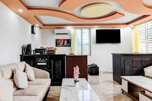 A living room with a sofa, a coffee table with a vase, a TV, and a reception desk. - Classic With Balcony Mourigram Near Andul Road (Howrah)