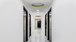 A hallway with a marble floor, white walls, and doors on both sides. - Classic With Balcony Mourigram Near Andul Road (Howrah)