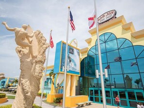 A building with a large glass facade, a statue of a figure, and multiple flags. - Stylish Loft Minutes From Beach Port - Unit 204 (Cape Canaveral)