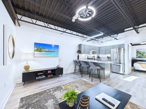 A modern kitchen with grey cabinets, stainless steel appliances, and a central island with bar stools. - Stylish Loft Minutes From Beach Port - Unit 204 (Cape Canaveral)