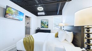 A modern bedroom with a bed, bedside table, lamp, and artwork. - Stylish Loft Minutes From Beach Port - Unit 204 (Cape Canaveral)