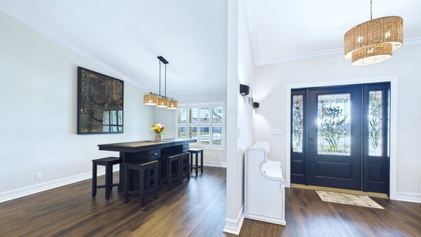 A spacious kitchen with a dark wood floor, a central island with stools, pendant lighting, and a dark front door with glass panels. - Indian Harbor Beach Pool Retreat (Indian Harbour Beach)