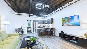Una cucina moderna con isola centrale, sgabelli da bar e zona pranzo con divano e tavolino.