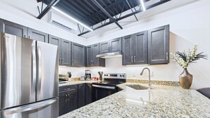 Una cucina moderna con piani di lavoro in granito, elettrodomestici in acciaio inossidabile e mobili scuri.