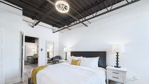 A modern hotel room with a large bed, bedside tables, and a ceiling fan. - Sleek Coastal Loft Close to Port Beach -unit 205 (Cape Canaveral)