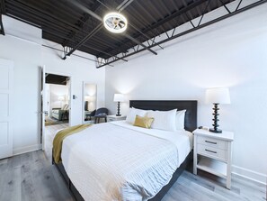 Ein Hotelzimmer mit einem großen Bett, Nachttischen, einem Schreibtisch und einem Spiegel.