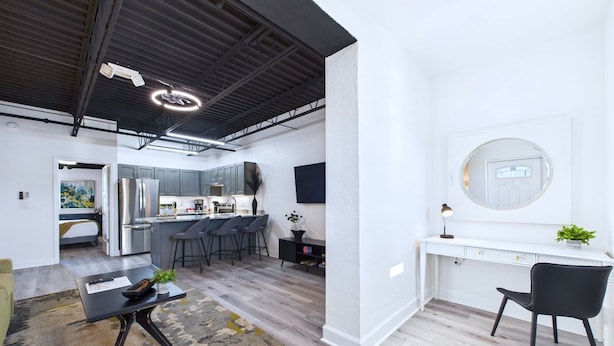 Una cucina moderna con elettrodomestici in acciaio inossidabile, un angolo bar e un tavolo consolle bianco con uno specchio.