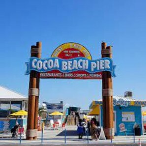 Señalización de Cocoa Beach Pier, con vista despejada hacia la entrada del muelle y sus alrededores.