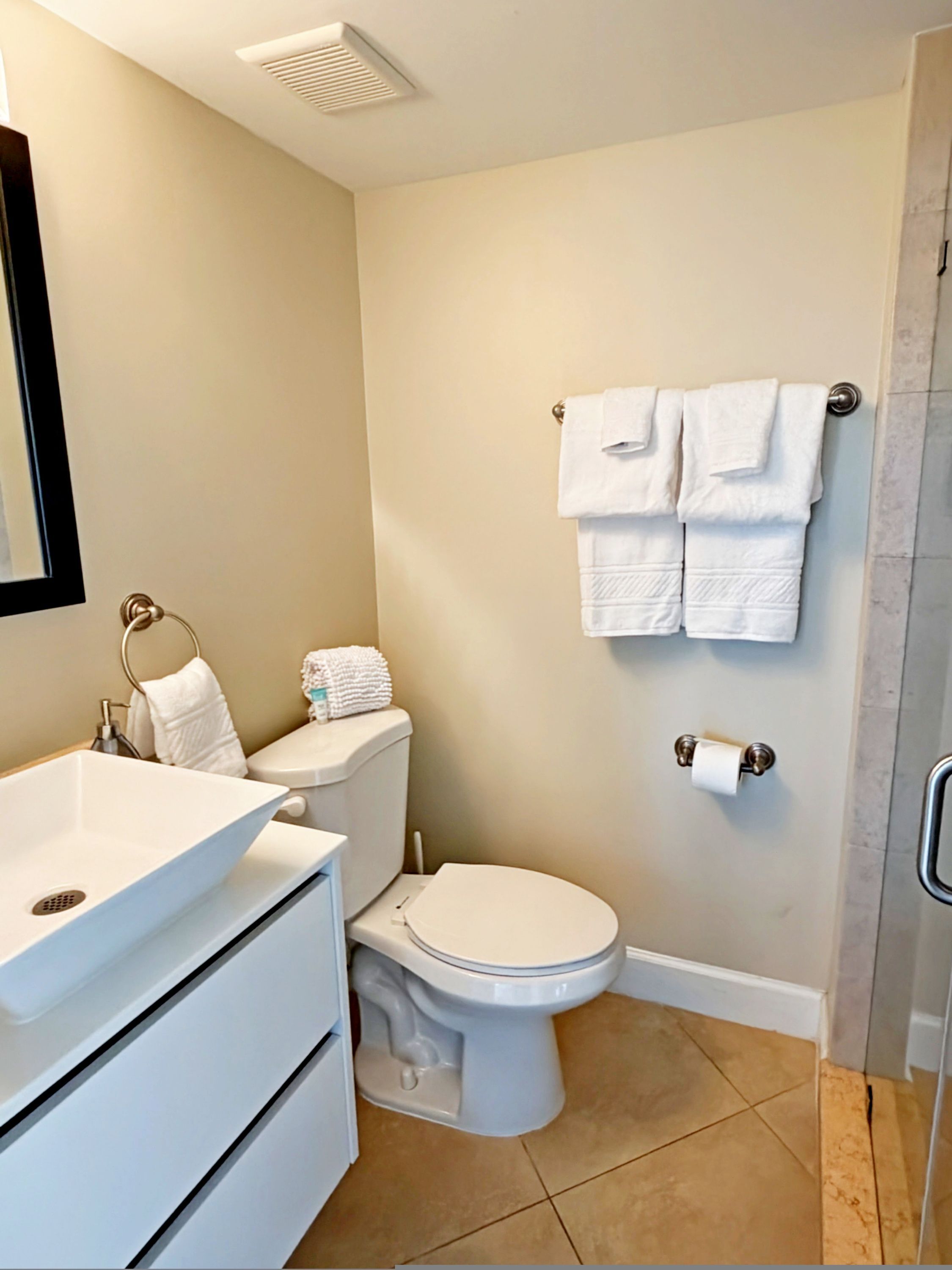 A bathroom with a white sink, toilet, and a towel rack with two towels.