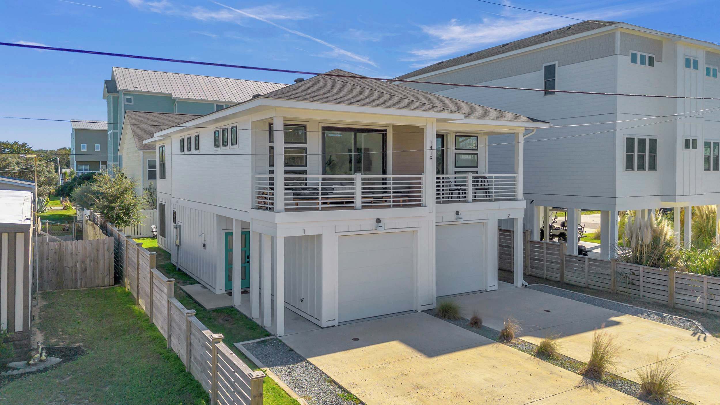 Um edifício residencial de dois andares com varanda, garagem e quintal cercado.