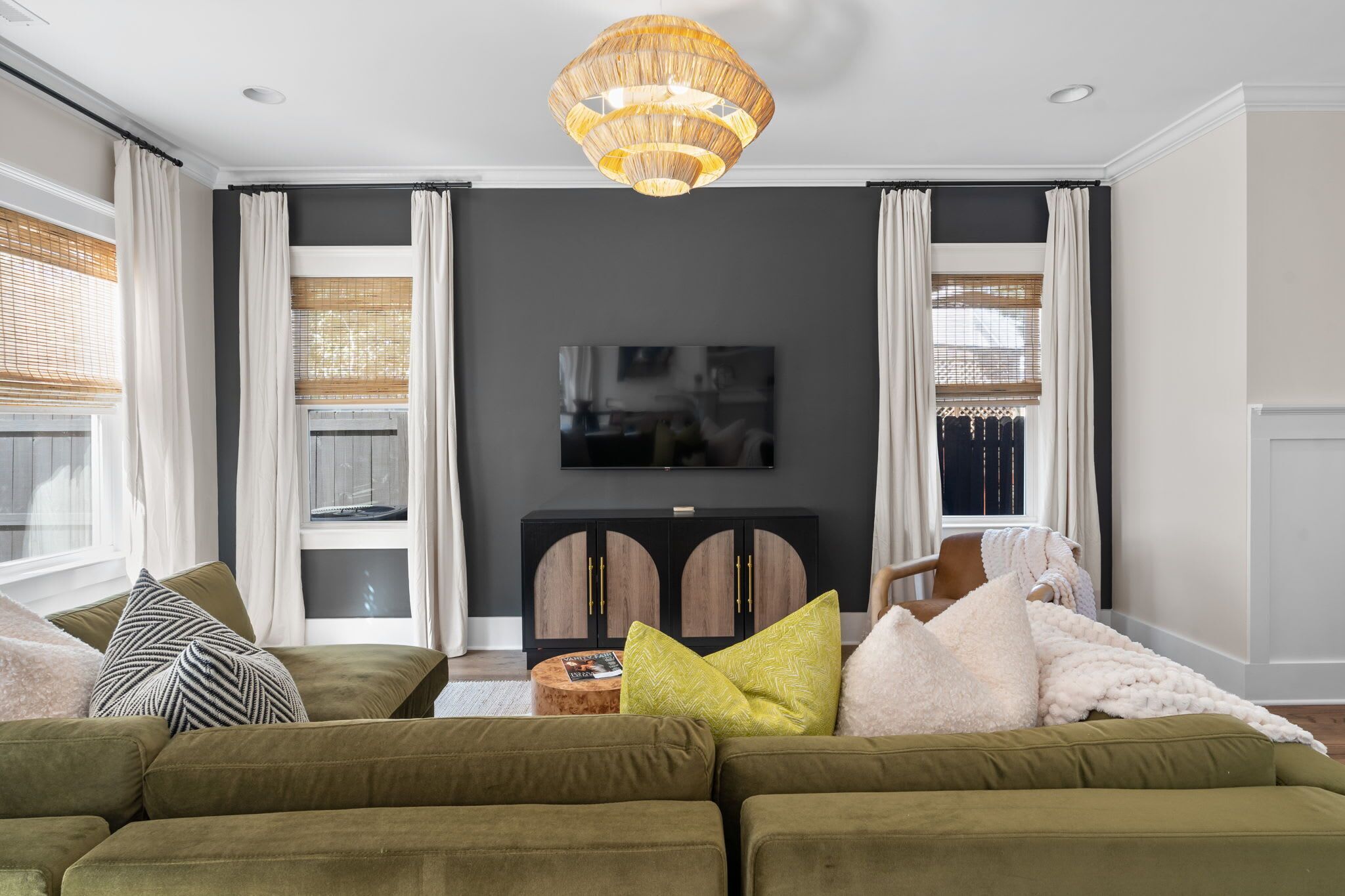 Een woonkamer met een grote zithoek, een televisie en een decoratieve plafondlamp.