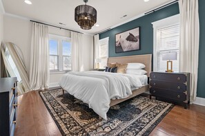 A bedroom with a large bed, a dresser, a rug, and a ceiling light fixture. - Downtown Wilmington | Walk to Riverwalk & Live Oak (Wilmington)