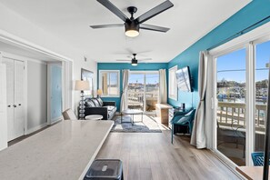 Uma sala de estar moderna com ventilador de teto, sofá, mesa de centro e vista da cidade através de amplas janelas.