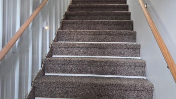 A carpeted staircase with wooden handrails, leading to a room with a kitchenette. - Cozy 1-bedroom apartment in pleasant Camanche with AC. On the Mississippi River (Camanche)