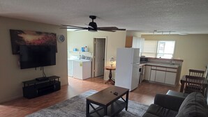 A living room with a sofa, a coffee table, a TV, and a ceiling fan. - Cozy 1-bedroom apartment in pleasant Camanche with AC. On the Mississippi River (Camanche)