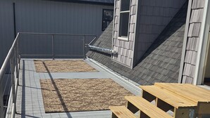 A rooftop terrace with a wooden table and benches, a patterned rug, and a metal railing. - Cozy 1-bedroom apartment in pleasant Camanche with AC. On the Mississippi River (Camanche)