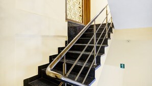 A staircase with black marble steps and metal handrails, leading to a wooden door. - Deluxe Lalganesh Formally Royal Avenue (Guwahati)