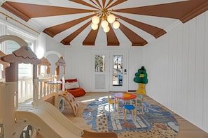 A children's play area with a slide, play structures, and a round table with chairs.