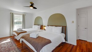 Une chambre d’hôtel avec deux lits, un ventilateur de plafond, une fenêtre avec des rideaux et une porte.