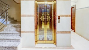 An elevator with a glass door and a metal handrail beside a staircase. - Single Room Madiwala Lake Park (Bengaluru)
