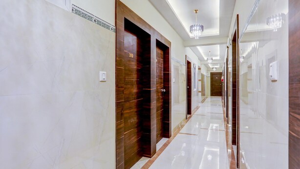 A hotel corridor with marble walls, wooden doors, and a shiny floor. - Single Room Madiwala Lake Park (Bengaluru)