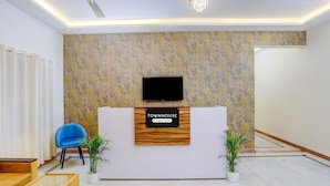 A reception area with a sign reading 'TOWNHOUSE & Company Serviced,' a ceiling fan, a chandelier, and two potted plants. - Single Room Madiwala Lake Park (Bengaluru)