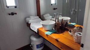 Une salle de bain avec un meuble-lavabo en bois, deux vasques, un grand miroir et un porte-serviettes.