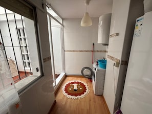 A narrow kitchen with a washing machine, a blue basin, and a lion-themed mat on the floor. - Vacation apartment just 100m from the beach -Vacation apartment just 100m from the Beach (San Pedro del Pinatar)