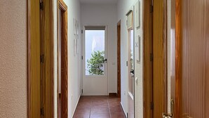 Un passadís amb portes de fusta, un sòl de rajola i una finestra al final.
