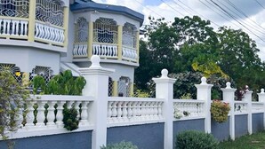 Ein zweistöckiges Haus mit Balkon, weißen Wänden und einem Zierzaun.