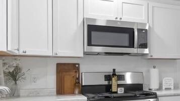 Una cucina moderna con mobili bianchi, elettrodomestici in acciaio inossidabile e un piano di lavoro in marmo.