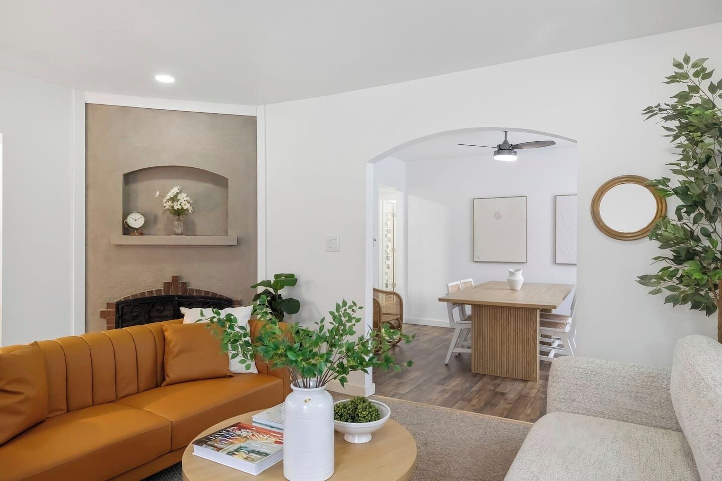 A living room with a sofa, a coffee table with books, a fireplace, and a dining area with a table and chairs.