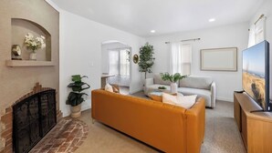 Una sala de estar con chimenea, un sofá, un televisor y una planta.