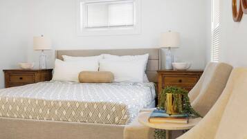 A bedroom with a bed, bedside tables, a lamp, a chair, and a window.