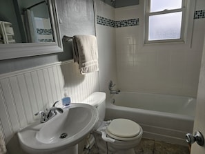 A bathroom with a white sink, toilet, and bathtub.