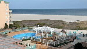 Resort com área de piscina, vista para a praia e um edifício grande.