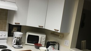Cozinha com armários brancos, micro-ondas, cafeteira, torradeira e máquina de lavar louça.