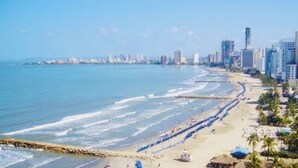 Paesaggio costiero con spiaggia, grattacieli e cielo sereno.