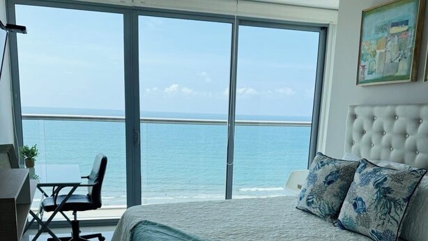 Una camera da letto con un letto grande, una scrivania, una sedia e vista sull'oceano.