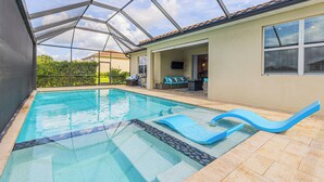 Una piscina con un recinto in vetro, una zona relax con posti a sedere e vista sul quartiere circostante.