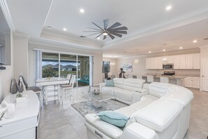A spacious living area with a white sofa, a dining table, and a kitchen in the background. - Spacious 3 Bed/3 Bath Pool Home (Naples)