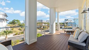 Ein überdachter Außenbereich mit Holzterrasse, einer Couch und Blick auf die Nachbarschaft.