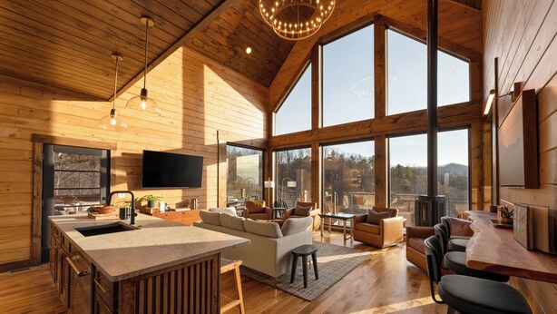 A spacious wooden interior with a large kitchen, dining area, and seating space with a view. - Luxury Smoky Mountain Cabin w/ Sauna (Sevierville)