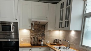 Een keuken met witte kastjes, een magnetron, een oven, een spoelbak, een vaatwasser en een wasmachine.